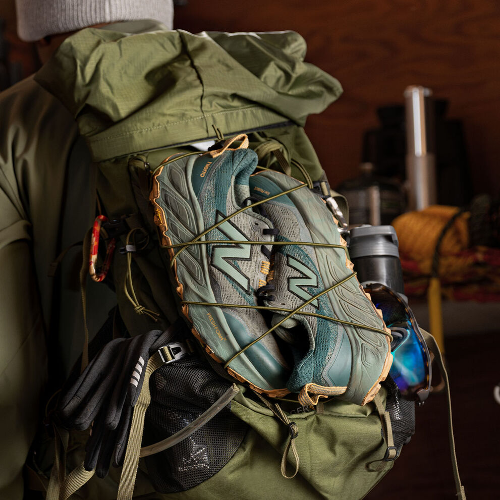 A pair of New Balance Fresh Foam X Hierro v9 strapped to a backpacking backpack